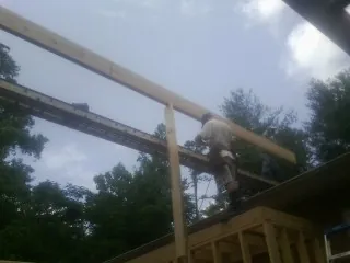 Carpenter setting a ridge beam over a new addition frame — Ice Dam Removal by Roofing Brothers in Harleyville
