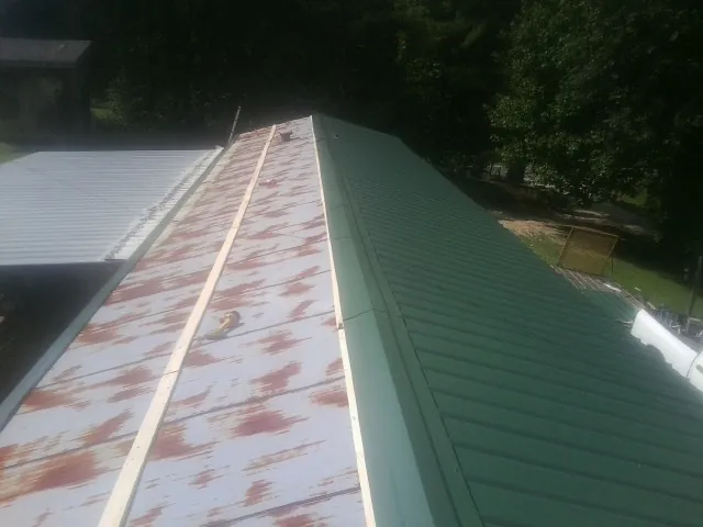 Old rusted panels beside newly installed green metal roofing — Wind Damage Roof Repair by Roofing Brothers in Harleyville