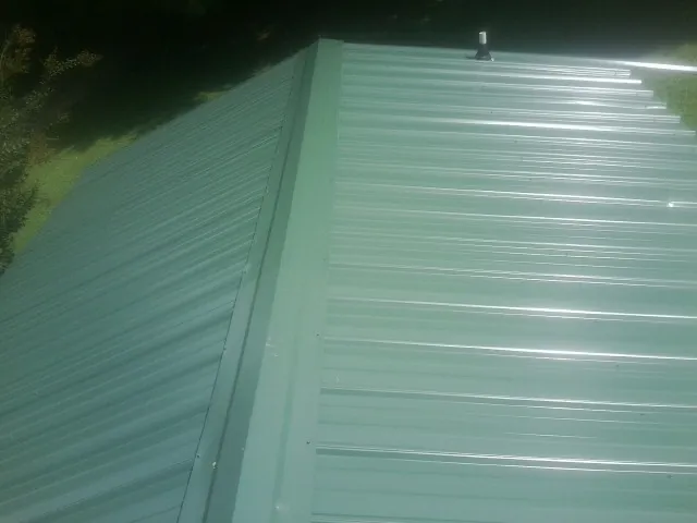 New green metal panels meeting at the ridge of a roof — Flat Roof Repair work by our crew in Harleyville
