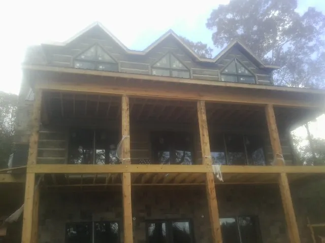 Dormers and porch framing on a large log home under construction — Roof Coating work by our crew in Harleyville