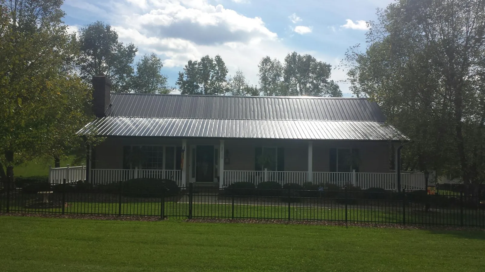 Gray metal roof on a brick ranch with a full width front porch — Gutter Guard Installation work by our crew in Harleyville