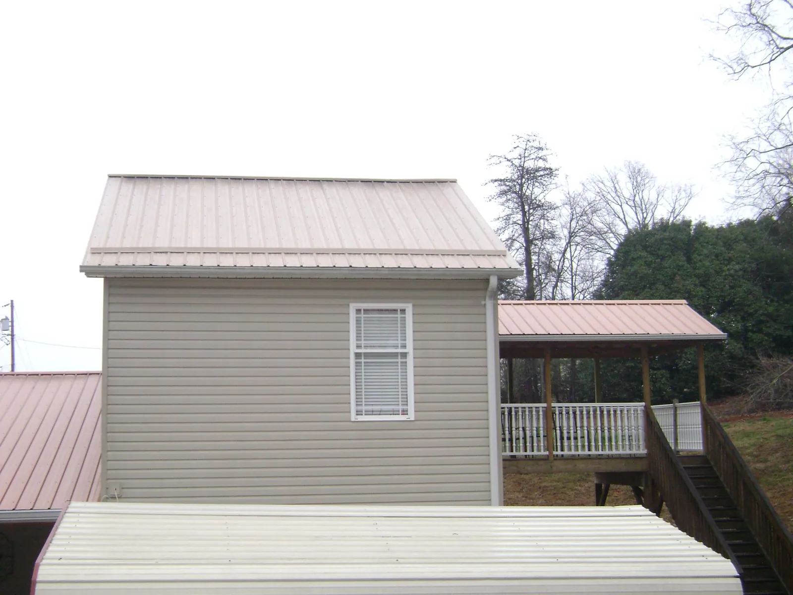 Tan metal roofs on a two story addition and attached porch, from a Roof Replacement job in Harleyville