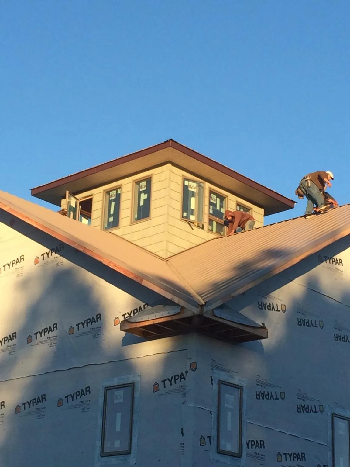 Roofers working around a rooftop cupola on a new metal roof at sunset — Roof Waterproofing in Harleyville by Roofing Brothers